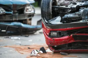A serious car crash where a red car is upside down and a blue car is wrecked.