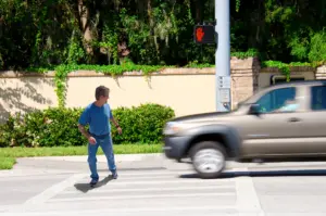 A man jaywalking and is about to get hit by a car.