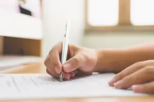 A person writing a form.